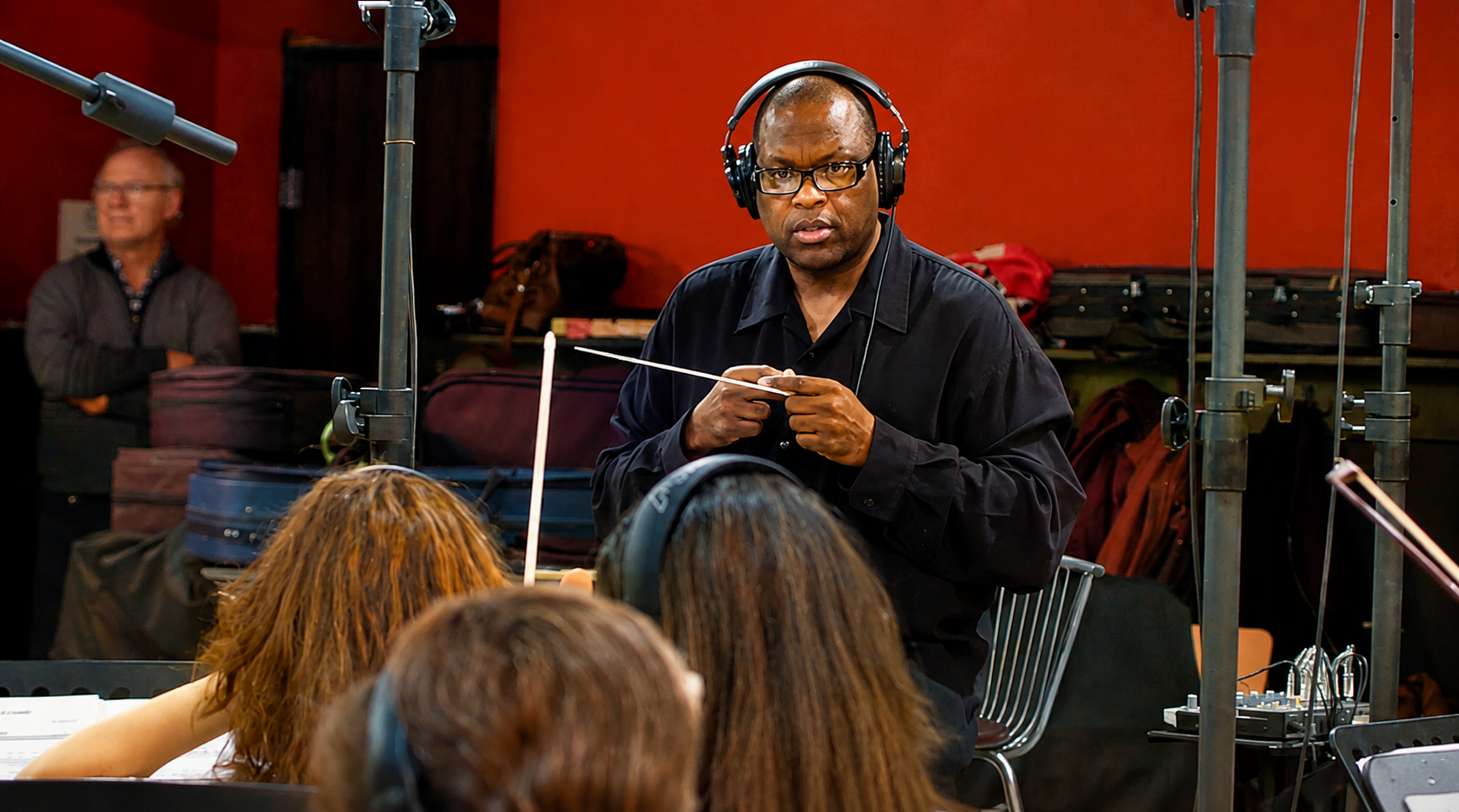 Rob Diggy Morrison conducting a string session with headphones and baton
